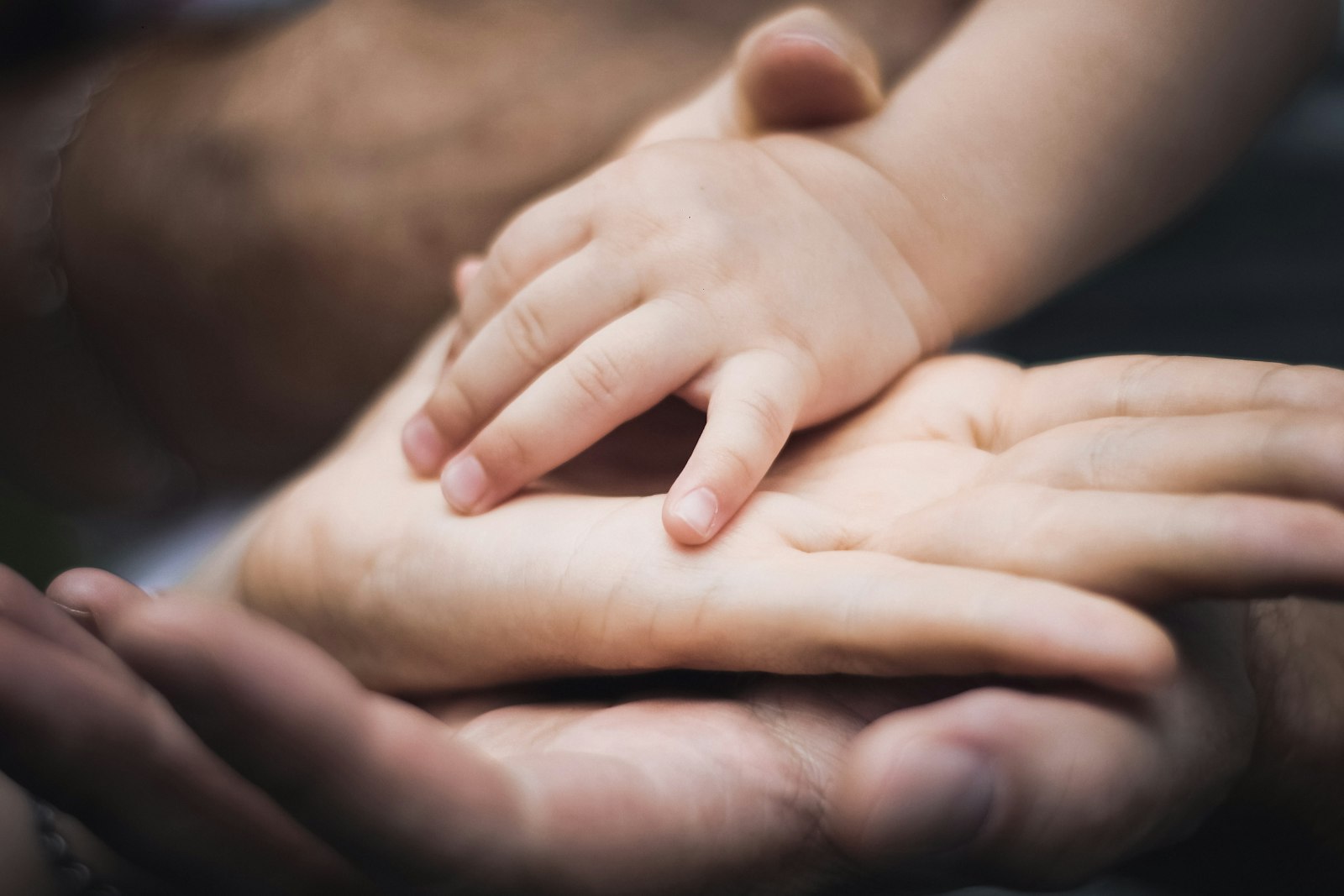 Mão de criança apoiada sobre a mão de um adulto